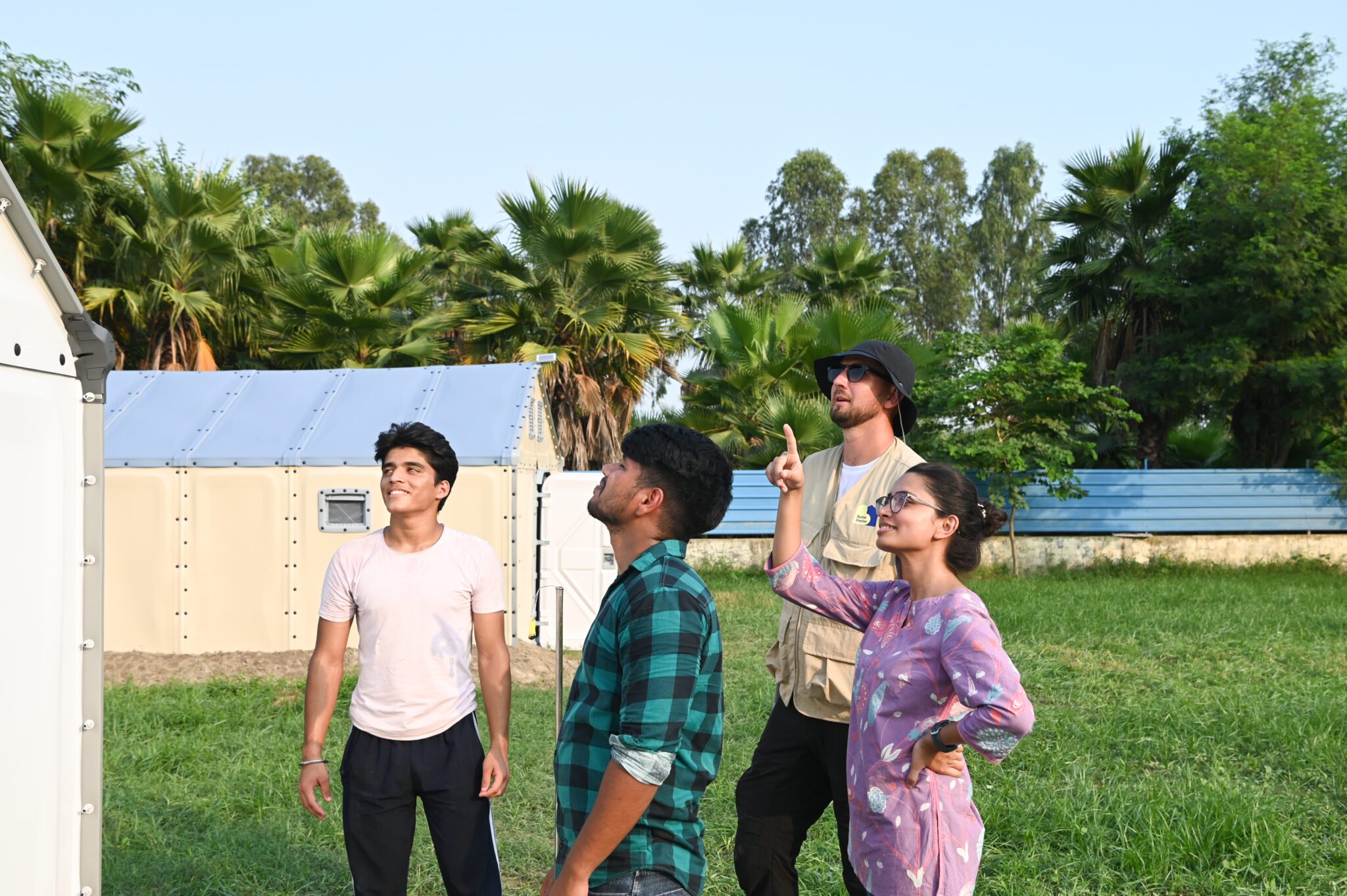 Every degree matters: testing and improving shelter temperatures with partners in India Four members of the project team standing outside the shelters, looking up as one of them points at the roof.
