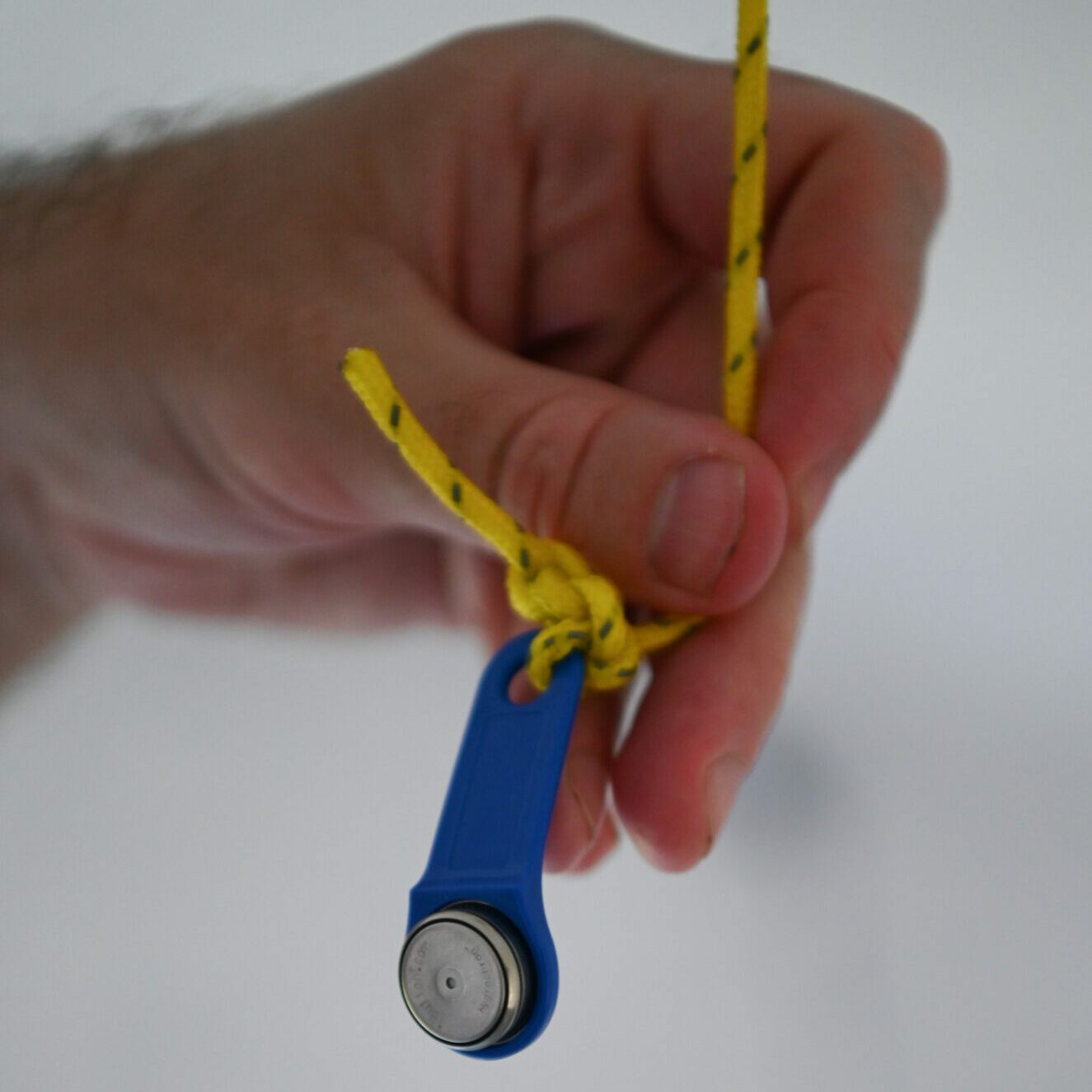 Every degree matters: testing and improving shelter temperatures with partners in India A hand holding a small blue temperature data logger tied to a yellow cord.